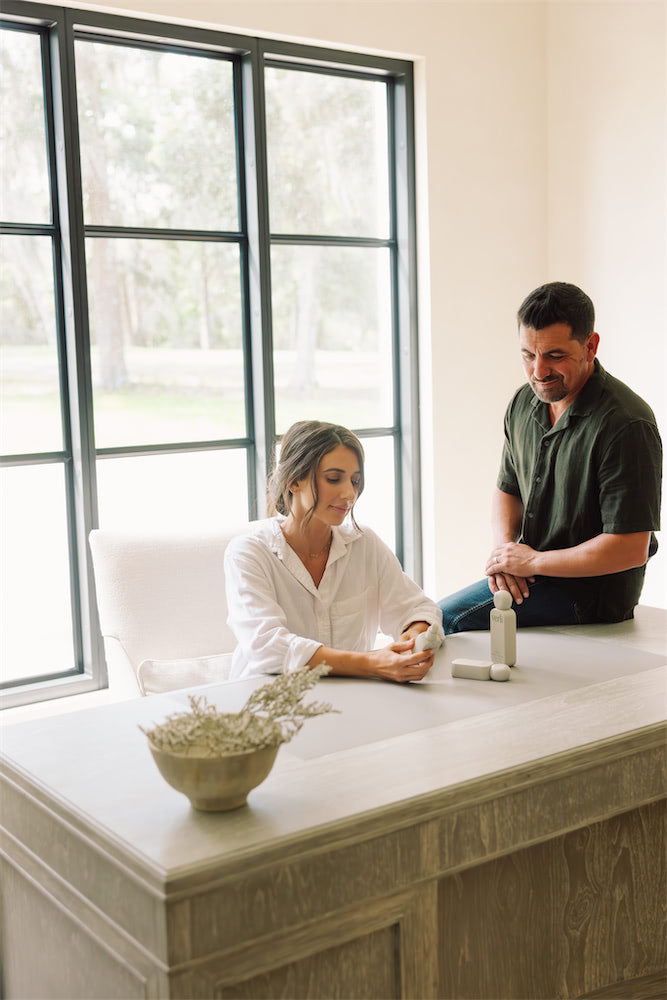 Laura and Marky sitting at a table with a large window in the background